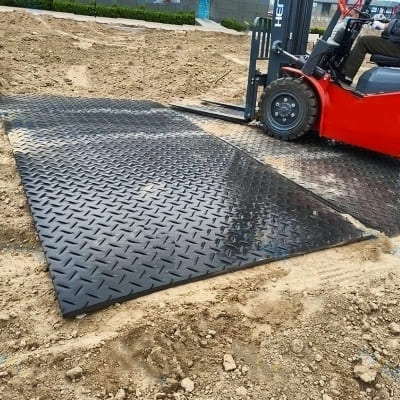 Heavy-duty composite construction mats protecting ground and equipment at a worksite.